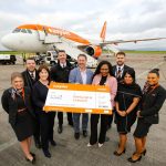 A group of people hold a large cheque outside a plane