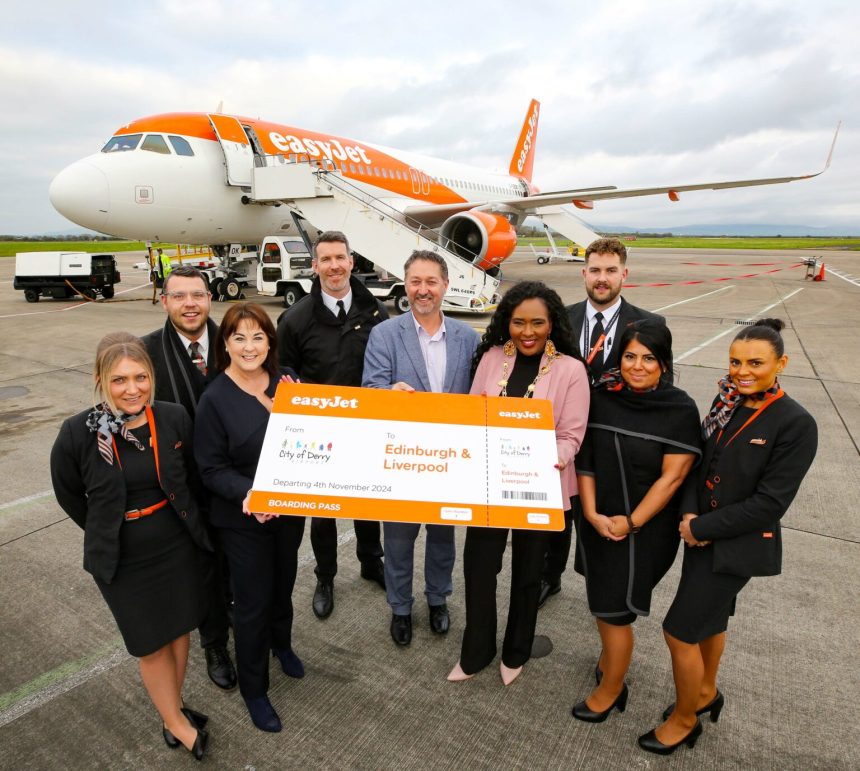 A group of people hold a large cheque outside a plane