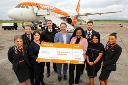 A group of people hold a large cheque outside a plane