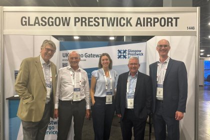 5 people stand below a sign saying Glasgow Prestwick Airport