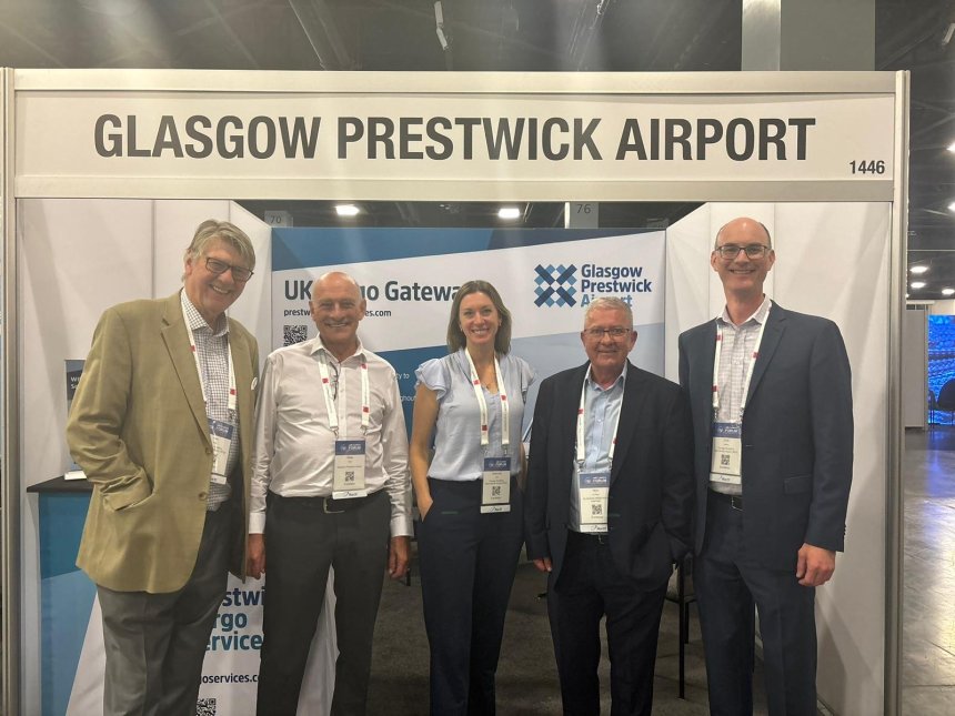 5 people stand below a sign saying Glasgow Prestwick Airport