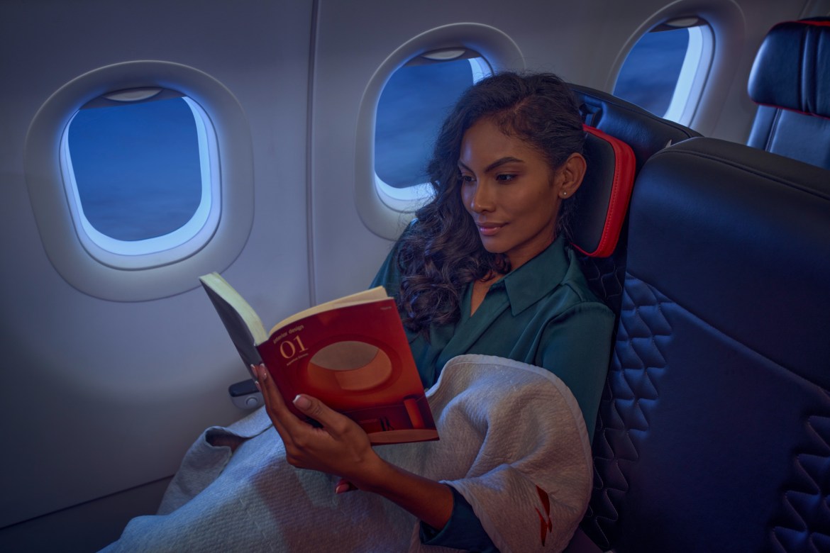 Passenger reading a book by the window on an Avianca flight, with sky visible outside.