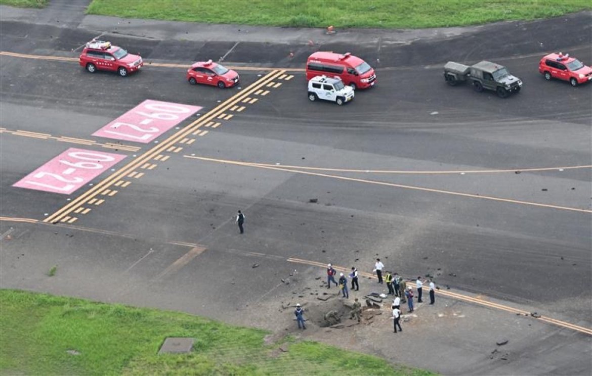 An image of the crater formed after the explosion of a bomb at Miyazaki airport and team of specialists around.