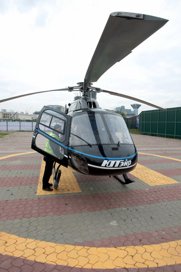 A Heliexpress Air Taxi with a black rotor and open door. 