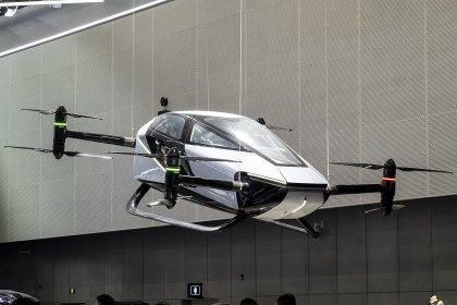 A white Xpeng X2 VTOL aircraft hovering in front of a building.